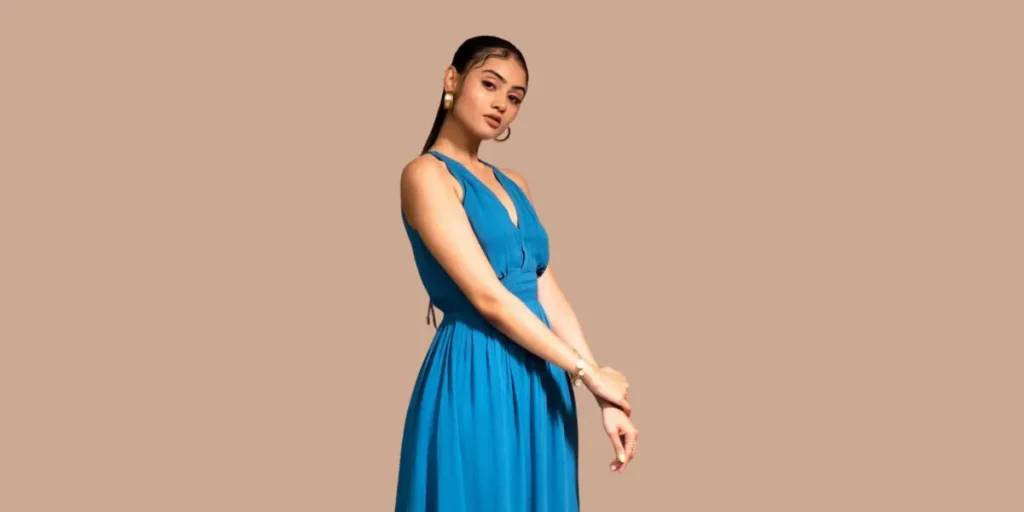 A Gujarati actress, Janki Bodiwala, in a sleeveless teal blue gown, poses against a beige background.