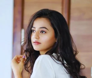 A Gujarati actress, Helly Shah, is giving a beautiful pose with open hair and wearing a white Western dress.