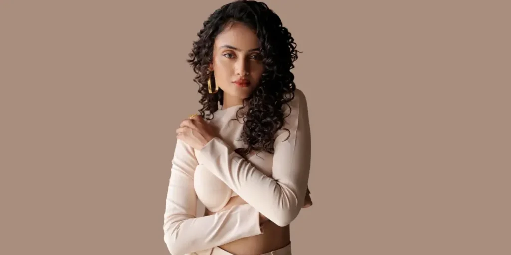 Janki Bodiwala, with voluminous curly hair, dressed in a soft beige co-ord set, gives an intense gaze that blends fashion with confidence.