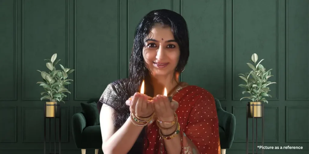 Neha Mehta in a red saree, holding lit diyas with a festive smile.