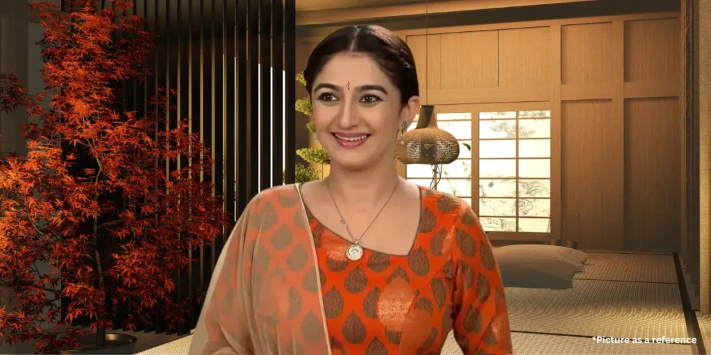 Neha Mehta in an orange ethnic dress, smiling indoors with decorative plants in the background.