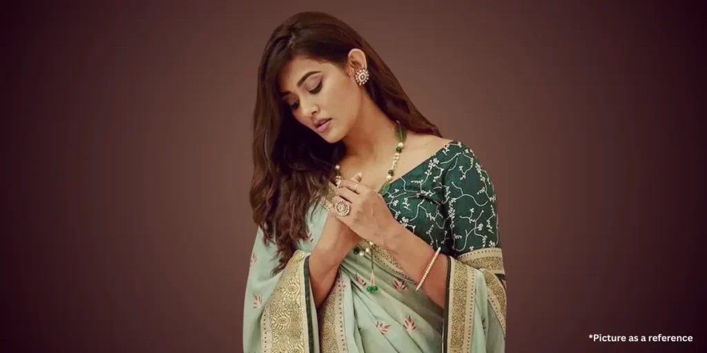 Pooja Jhaveri, in a green printed saree with jewelry, looked down thoughtfully.