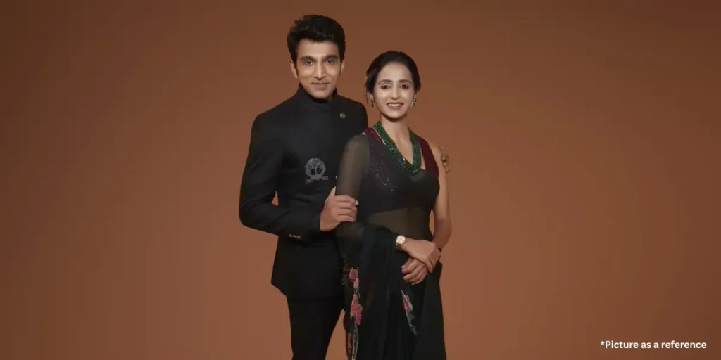 Pratik Gandhi and Bhamini Oza, dressed in coordinated black outfits, pose together with smiles against a brown backdrop.