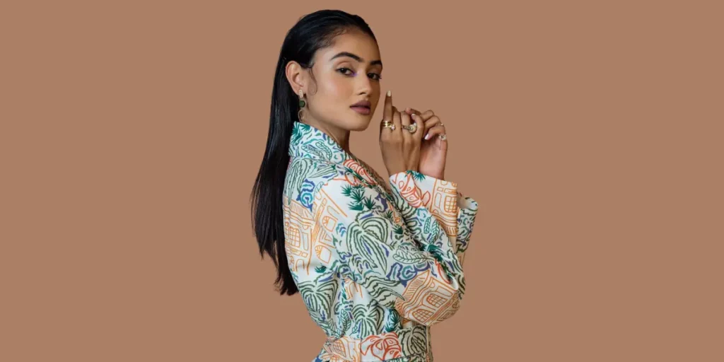 Trendy fashionista Janki Bodiwala is in a multicolored printed jacket dress, striking a poised profile pose with sleek hair and bold accessories.
