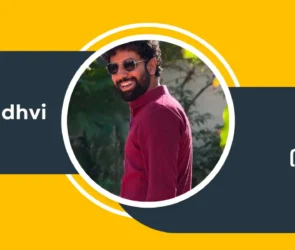 Mitra Gadhvi smiling while wearing a maroon kurta on a yellow and black circular design banner with text in Gujarati and English