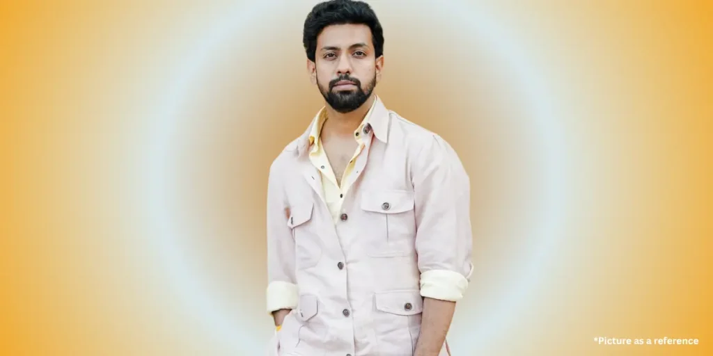 Writer and actor Mitra Gadhvi, in a light beige casual shirt with rolled sleeves, posing against a yellow gradient background
