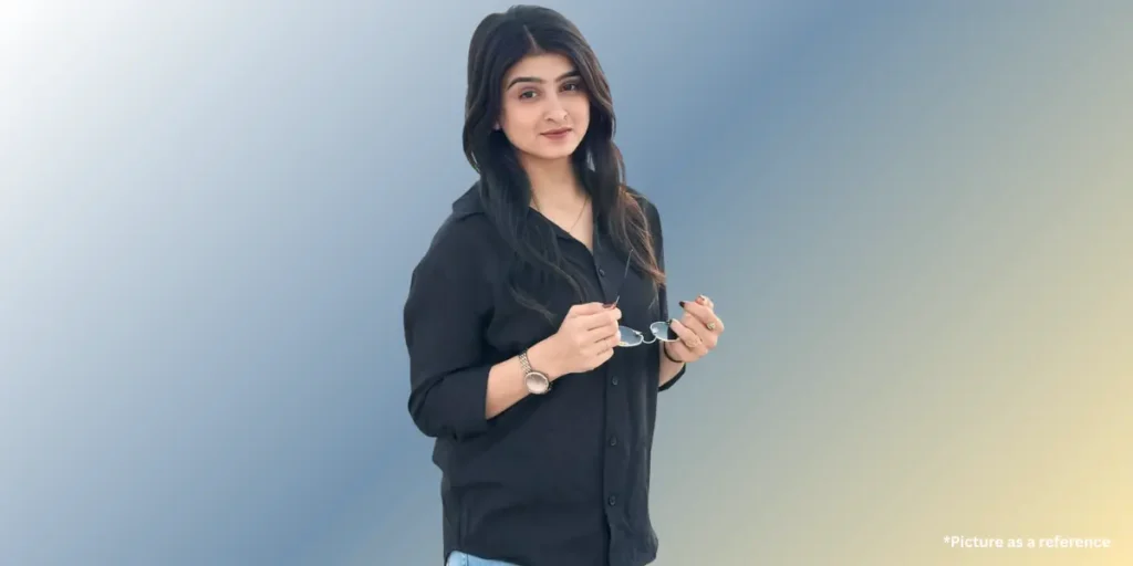 Actress Geet Thakkar in a smart casual look, wearing a black shirt and holding eyeglasses.