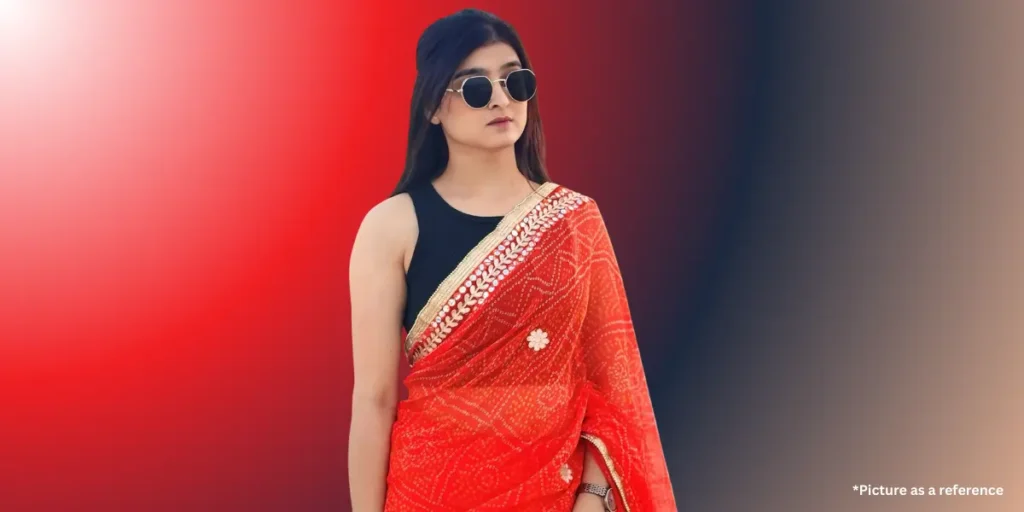 Geet Thakkar in a modern-fusion look, wearing a red bandhani-style saree with a black sleeveless top and sunglasses.