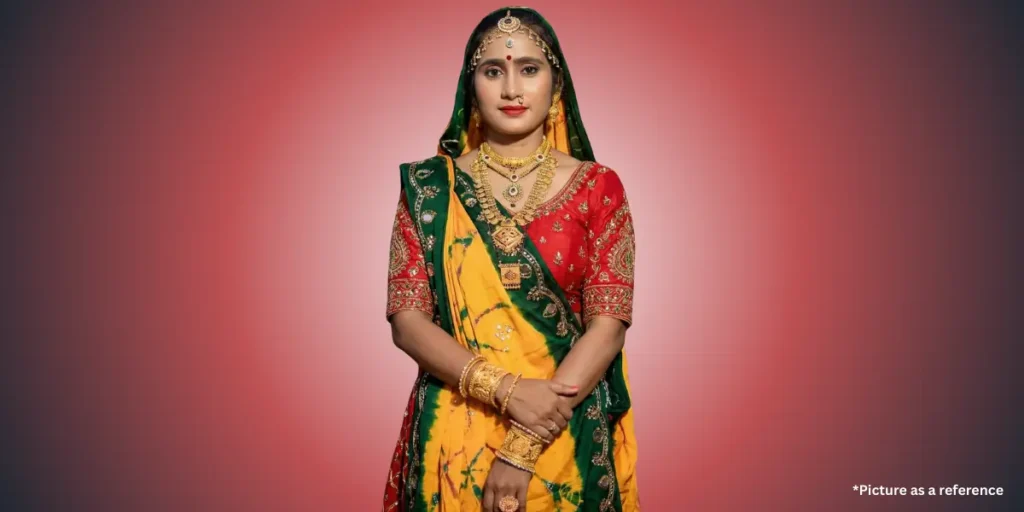 A woman, Hansha Bharvad, wearing a traditional yellow, green, and red Gujarati chaniya choli, or ghagra, with gold jewelry.