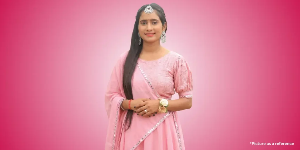 Hansha Bharwad is smiling, dressed in a modern pastel pink Indian outfit, possibly a lehenga or sharara.