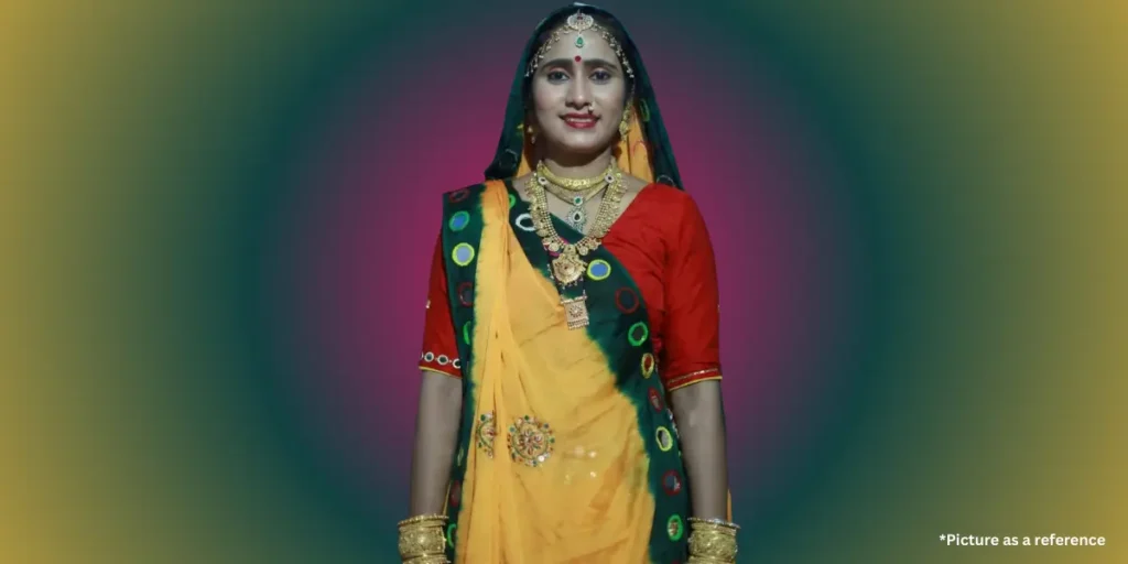 Hansha Bharwad is smiling in a traditional Indian outfit with a red blouse and a bright yellow and dark green bandhani, or tie-dye dupatta, accessorized with layered gold necklaces.