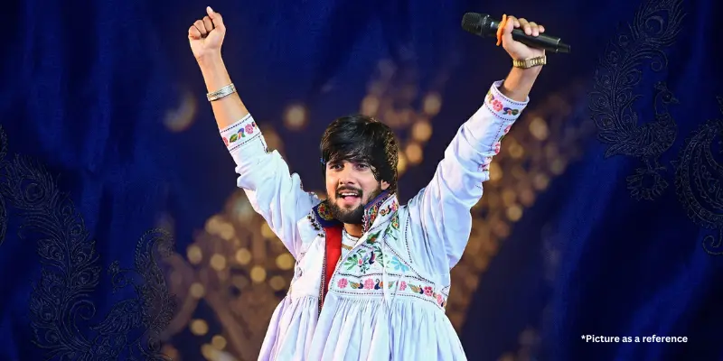 Singer Gopal Bharvad performing in traditional white Gujarati folk attire (Kediyu) with hands raised on stage.