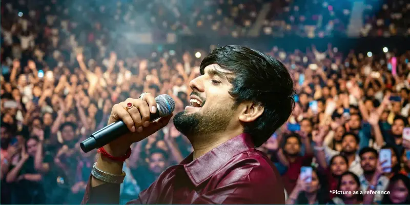 Side profile of singer Gopal Bharwad singing into a microphone during a crowded live concert.