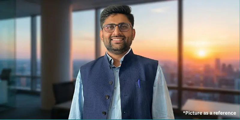 Politician Gopal Italiya posing in a blue jacket against a sunset skyline of the city.