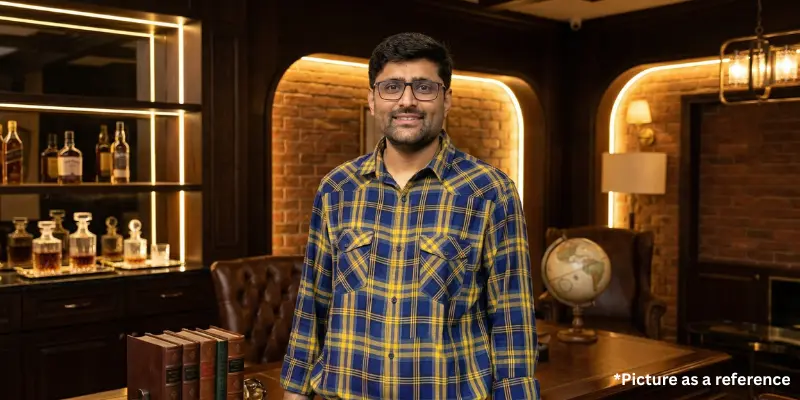 Gopal Italiya wearing a yellow and blue checkered shirt in a classic wooden library setting.