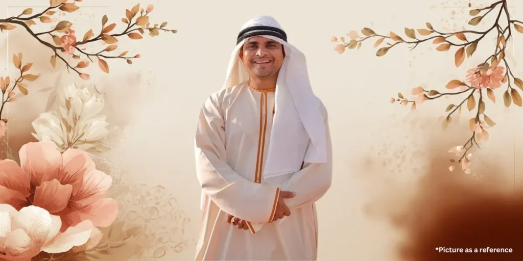 Nitin Jani (Khajur Bhai) wearing a white Thobe and Ghutra (traditional Arab dress) in a soft aesthetic edit with peach floral branches.