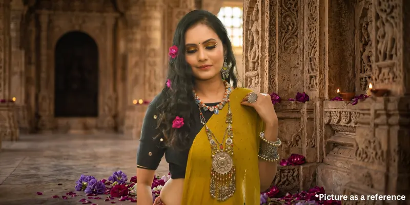 Chini Raval in traditional Indian attire, wearing a black blouse and a yellow dupatta with heavy silver oxidized jewelry.