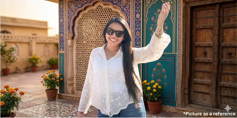 Singer Neha Suthar is waving and smiling in a white, patterned shirt and sunglasses.