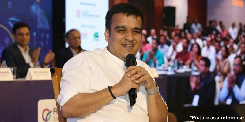 Harsh Sanghavi interacting during a meeting or press conference, holding a microphone and smiling at the audience.