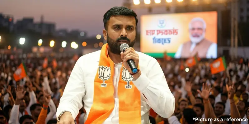 Raju Karpada addressing a massive public gathering while wearing an orange party scarf during an official campaign.