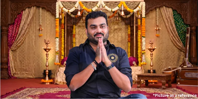 Singer Jignesh Kaviraj offering a namaste greeting in a temple-style setting with oil lamps and floral decorations.