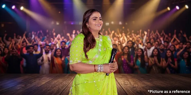 Singer Kajal Maheriya is wearing a bright neon green saree, holding a microphone, with a large crowd visible in the background.
