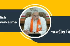 Jagdish Vishwakarma is wearing a BJP saffron scarf and sitting in an office, and his name is written in Gujarati and English.