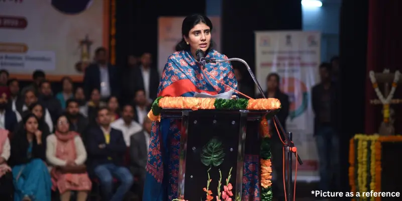 Rivaba Jadeja addressing a public gathering from a floral-decorated podium.